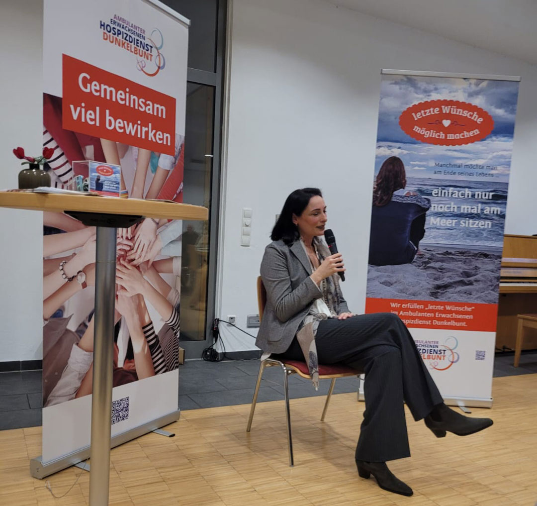 Heike Schöttler mit Mikrofon vor zwei Rollups
