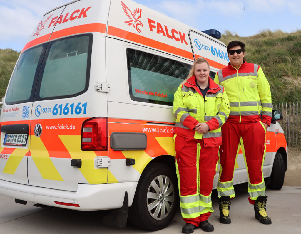 Zwei Rettungssanitäter stehen vor einem Rettungswagen